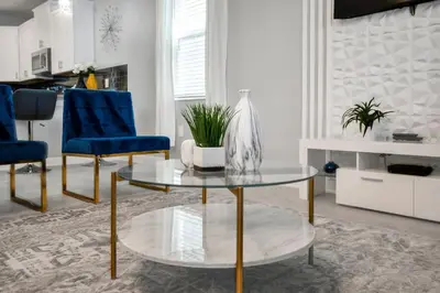 a living room with a glass table and blue chairs at Magical Mickey Home 8 minutes from Disney STL109 in Kissimmee