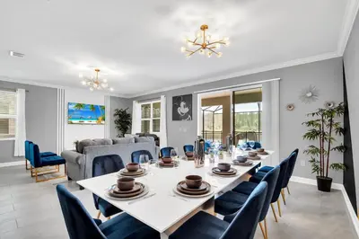 a dining room with a white table and blue chairs at Magical Mickey Home 8 minutes from Disney STL109 in Kissimmee