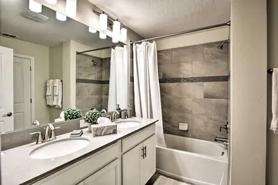 a bathroom with a sink and a tub and a sink and a mirror at The Windermere - Pool Lazy River & Waterslides in Kissimmee