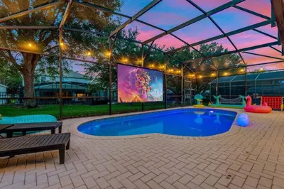 a swimming pool in a tent with a large screen at Immersive Themed Villa in Resort 4mi to Disney with Game Room and Private Pool in Orlando