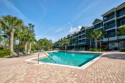 a swimming pool with palm trees and a building at Modern 3BR Condo Near Disney- Pool in Orlando
