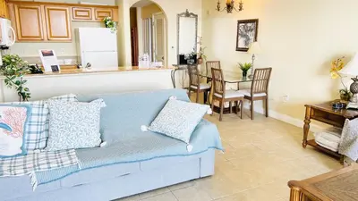 a living room with a blue couch and a kitchen at Blue Heron Beach Resort pet friendly in Orlando