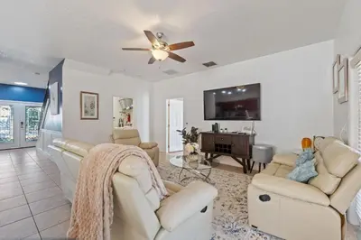 a living room with white furniture and a ceiling fan at Enjoyable 6BR Home Near Disney in Orlando