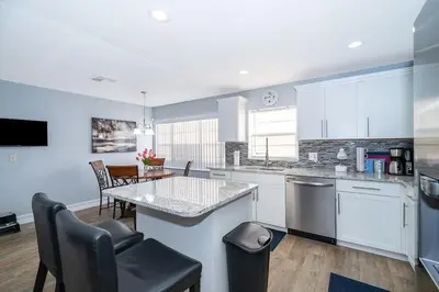 a kitchen with white cabinets and a table and chairs at Private Paradise! Stunning south-facing pool home in Kissimmee