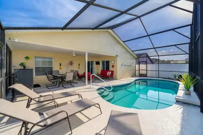 a patio with a swimming pool with chairs and a table at Private Paradise! Stunning south-facing pool home in Kissimmee