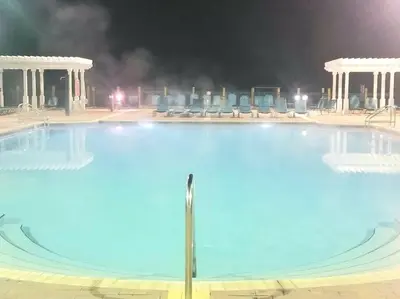 a large swimming pool at night with blue water at The Villas at Seven Dwarfs - 2624 Mickey Villa - Near Disney - Water Park in Kissimmee