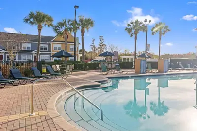 a swimming pool at a resort with chairs and palm trees at The Villas at Seven Dwarfs - 2603 Amazing Luxury Villa - Near Disney - Water Park in Kissimmee