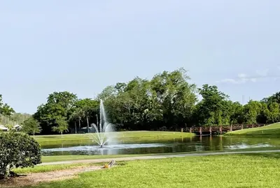 a fountain in the middle of a pond with a bridge at Stunning Ventura Condo in Orlando