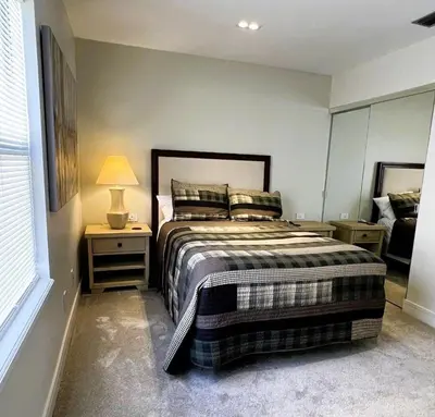 a bedroom with a bed and a lamp and a window at Stunning Ventura Condo in Orlando