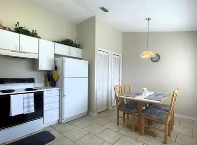 a kitchen with a table and a white refrigerator at Ventura Village Cottage Grove Townhome in Orlando