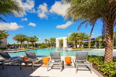 a swimming pool with chairs and palm trees at Beautiful and cozy home at Sonoma Resort in Kissimmee