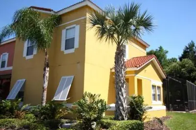 a yellow house with two palm trees in front of it at Perfect vacation Gated Resort with Private Pool in Kissimmee