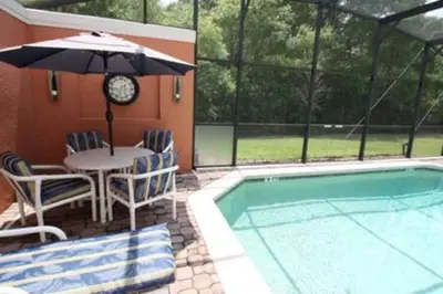 a table and chairs with an umbrella next to a pool at Perfect vacation Gated Resort with Private Pool in Kissimmee