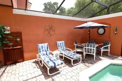 a patio with chairs and a table and an umbrella at Perfect vacation Gated Resort with Private Pool in Kissimmee