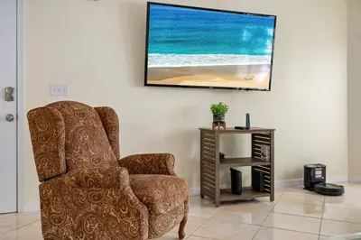 a living room with a chair and a flat screen tv at Spacious Bright Close to Disney with Pool and Gym in Kissimmee