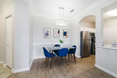 a kitchen and dining room with a table and blue chairs at Cozy Escape - Disney Universal SeaWorld in Orlando