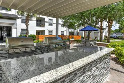 a outdoor kitchen with two bbqs and an umbrella at Cozy Escape - Disney Universal SeaWorld in Orlando