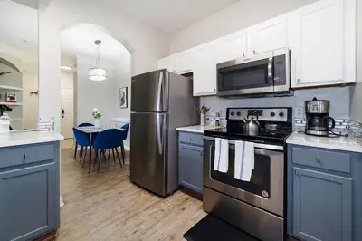 a kitchen with stainless steel appliances and blue cabinets at Cozy Escape - Disney Universal SeaWorld in Orlando