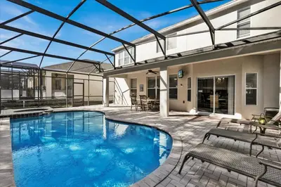 a swimming pool with two chairs and a patio at Royal Retreat in Orlando