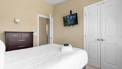 a bedroom with a white bed with a clock on it at Sunny Summer Stay - Renovated TownHome by Disney! in Orlando