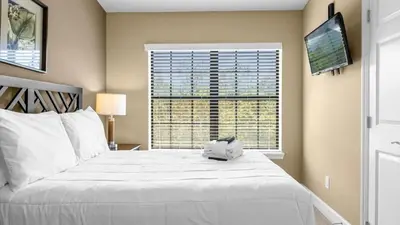 a bedroom with a large white bed and a television at Sunny Summer Stay - Renovated TownHome by Disney! in Orlando