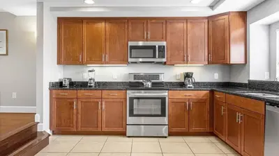 a kitchen with wooden cabinets and stainless steel appliances at Family Summer Trip - Renovated TownHome by Disney! in Orlando