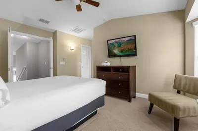 a bedroom with a white bed and a chair at Sunny Summer in FL - Relax in a TownHome by Disney! in Orlando