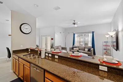 a kitchen and living room with a clock on the wall at 8953 Candy Palm Road in Kissimmee