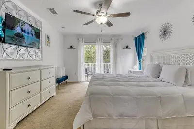 a white bedroom with a bed and a ceiling fan at Stunning 5 bedroom pool home in gated community minutes from Disney in Kissimmee