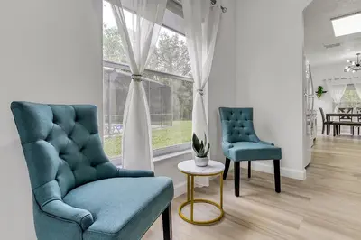 two chairs and a table in a living room at Stunning 5 bedroom pool home in gated community minutes from Disney in Kissimmee