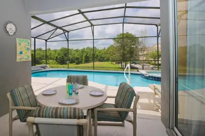 a dining table and chairs in front of a swimming pool at Luxury Villa Private Pool And Great Game Room in Kissimmee
