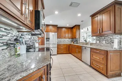 a large kitchen with wooden cabinets and granite counter tops at 10 Mi to Disney World Lakeside Orlando Getaway! in Orlando