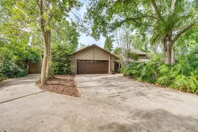 a house with a garage and trees and a driveway at 10 Mi to Disney World Lakeside Orlando Getaway! in Orlando