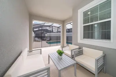a balcony with two white chairs and a table at 4816LN TOWNHOUSE 4 BEDROOMS 3 BATHROOMS PRIVATE POOL in Kissimmee