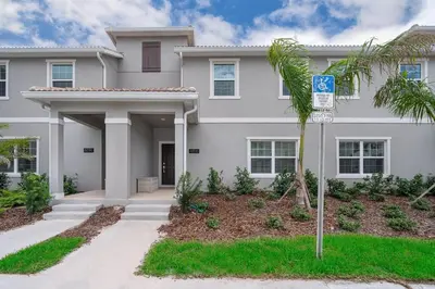 a white house with a palm tree in front of it at 4816LN TOWNHOUSE 4 BEDROOMS 3 BATHROOMS PRIVATE POOL in Kissimmee