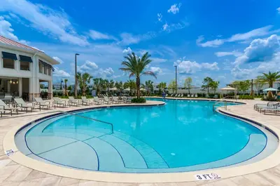 a large swimming pool with chairs and palm trees at 3120 Paradox Circle 301 in Kissimmee