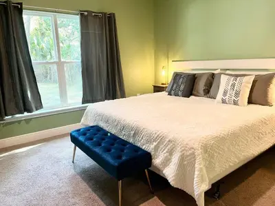 a bedroom with a large bed and a blue stool at Sweet Stay with fully fenced yard in Sanford