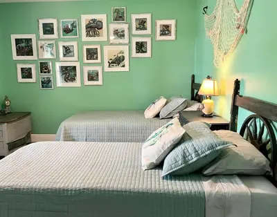 two beds in a bedroom with pictures on the wall at Sanford's Seahaven in Sanford