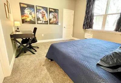 a bedroom with a bed and a desk with a computer at The Arcade close to downtown with fenced yard in Sanford