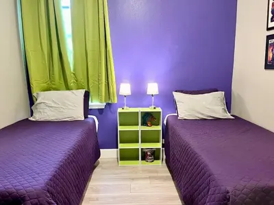 two beds in a room with purple and green at The Billiard close to downtown with fenced yard in Sanford