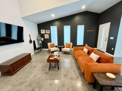 a living room with a large orange couch and chairs at The Butterfly House - with sauna in Sanford