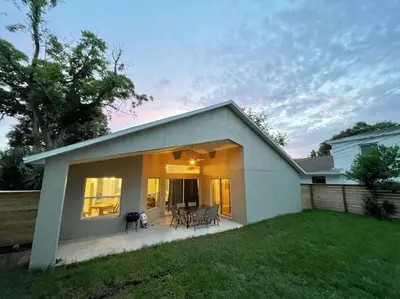a small white house with a patio in a yard at The Sanford Ave House with fully fenced yard in Sanford