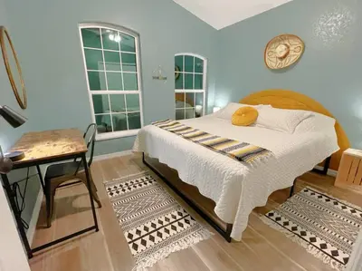 a bedroom with a bed and a table and windows at The Sanford Ave House with fully fenced yard in Sanford