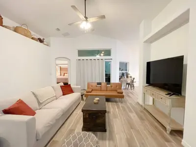a living room with a white couch and a flat screen tv at The Sanford Ave House with fully fenced yard in Sanford