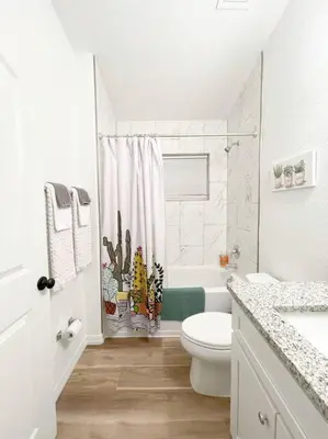 a white bathroom with a toilet and a shower at The Sanford Ave House with fully fenced yard in Sanford