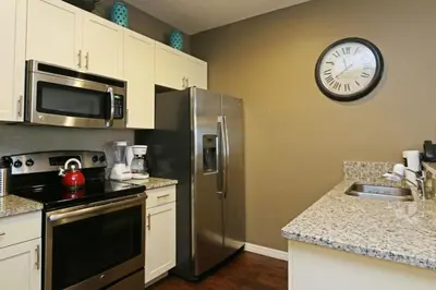 a kitchen with a refrigerator and a clock on the wall at Your VIP Home in Orlando Disney 25106 in Kissimmee