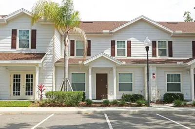 a white house with a palm tree in front of it at Your VIP Home in Orlando Disney 25106 in Kissimmee