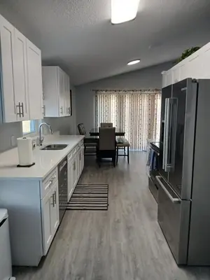 a kitchen with white cabinets and a kitchen with a table at Nard Jolie Kay in Kissimmee