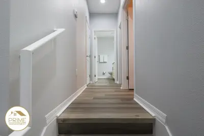 a hallway with white walls and a wooden floor at NEW Renewed 3BD Modern 10 Min to Disney in Kissimmee