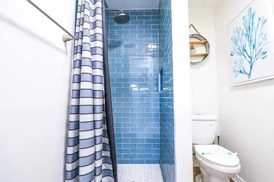 a bathroom with a blue shower curtain and a toilet at NEW5 LUXURYSTUDIO Nr DISNEY PETSOKprivENTRY in Kissimmee